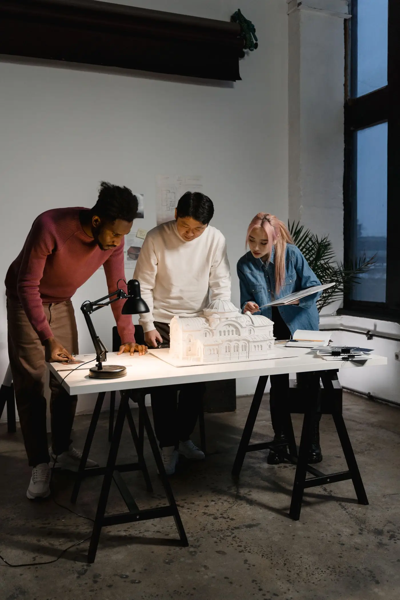 Team gathered around an architectural model in the studio.