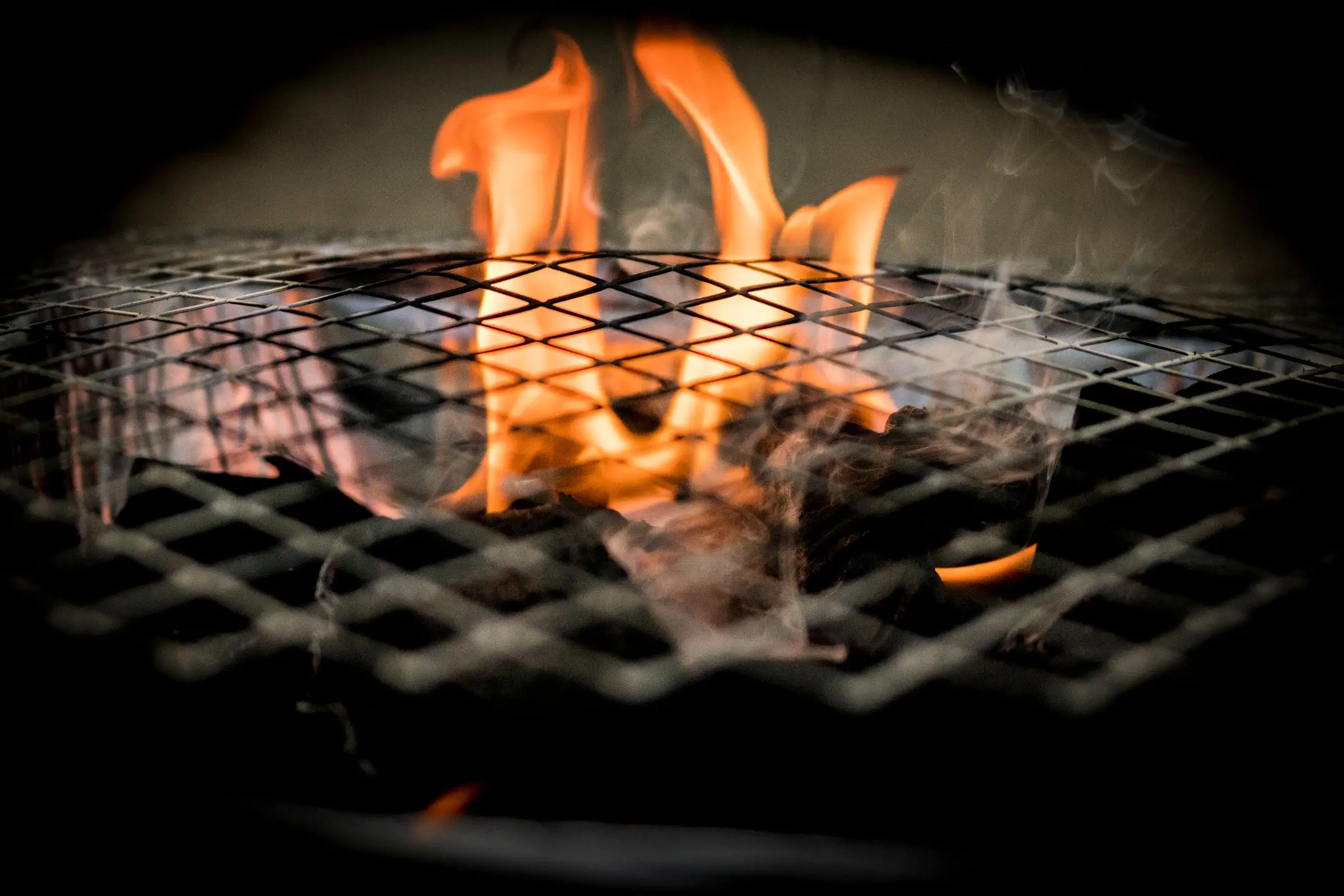 Flames rising over a grill grate.